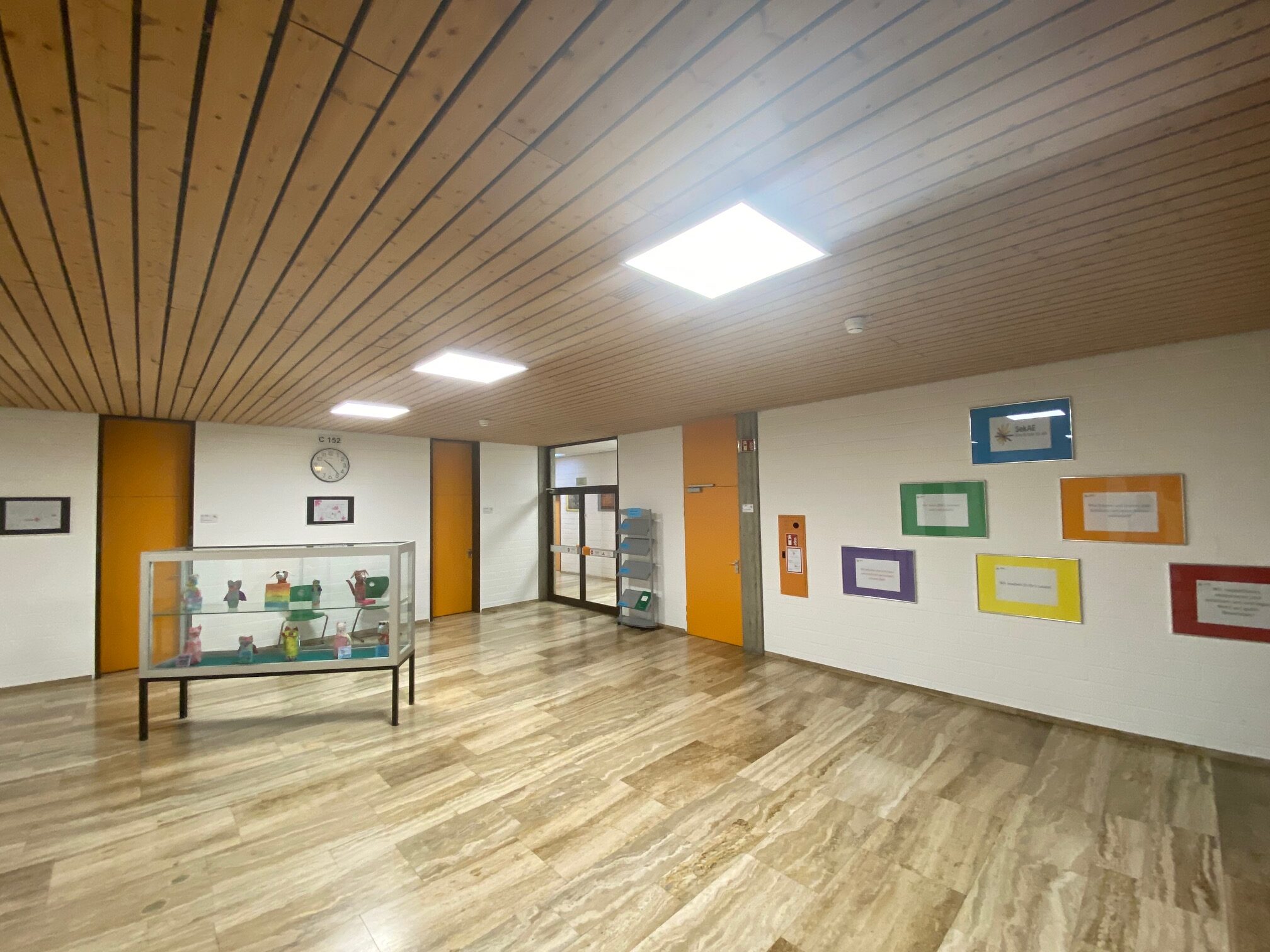 Räumlichkeit der SekAE mit Vitrine und farbigen Bildern an der Wand