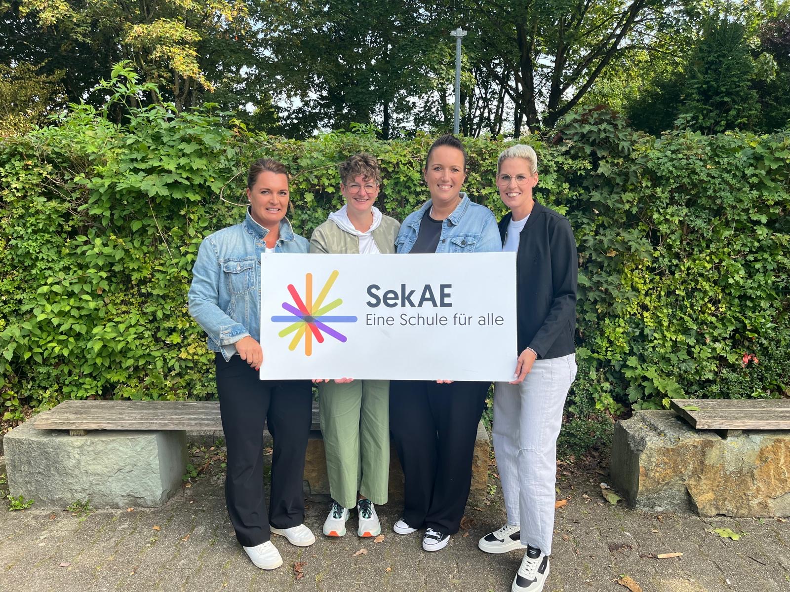 Vier Personen des Fördervereins halten ein Schild mit dem Logo der SekAE