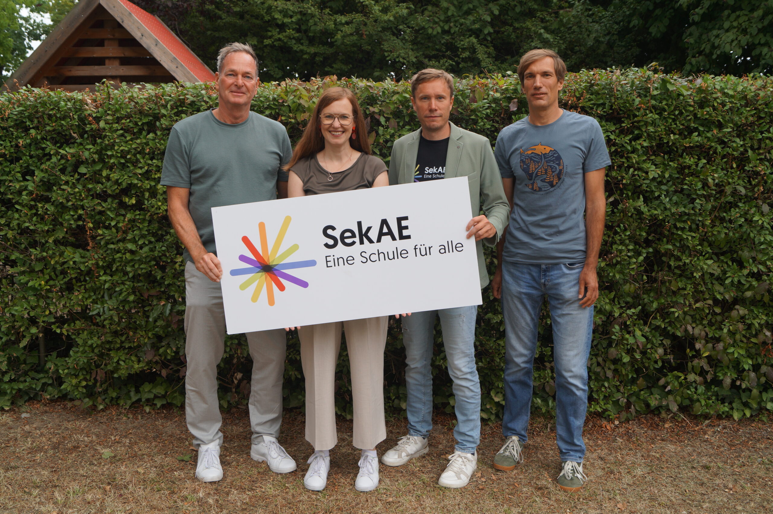 Vier Personen halten ein Schild mit dem Logo der SekAE