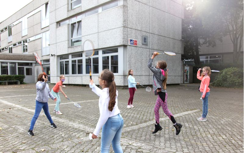 Kinder spielen Badminton auf dem Schulhof
